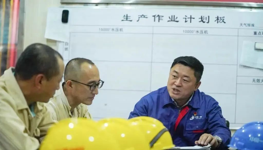刘伯鸣在厂房会议室内与工友讨论生产作业事项